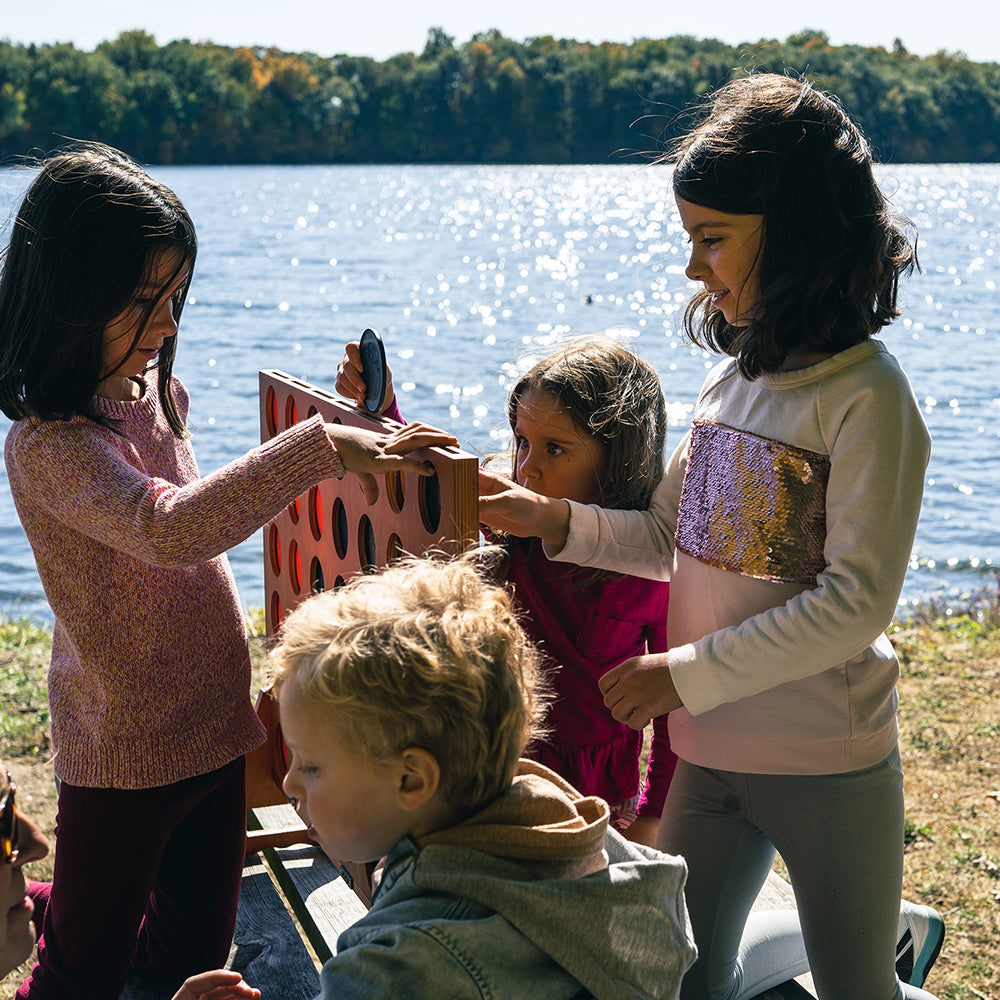 Kids Playing With Elakai Giant 4-In-A-Row Game With Lake In Background